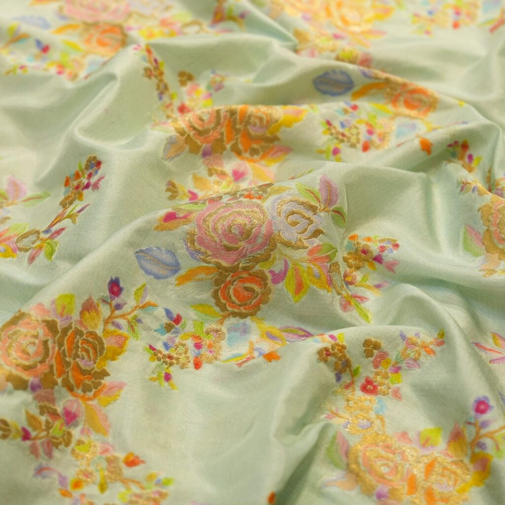 Mint green pure silk fabric with pastel floral motifs and golden Zari weave