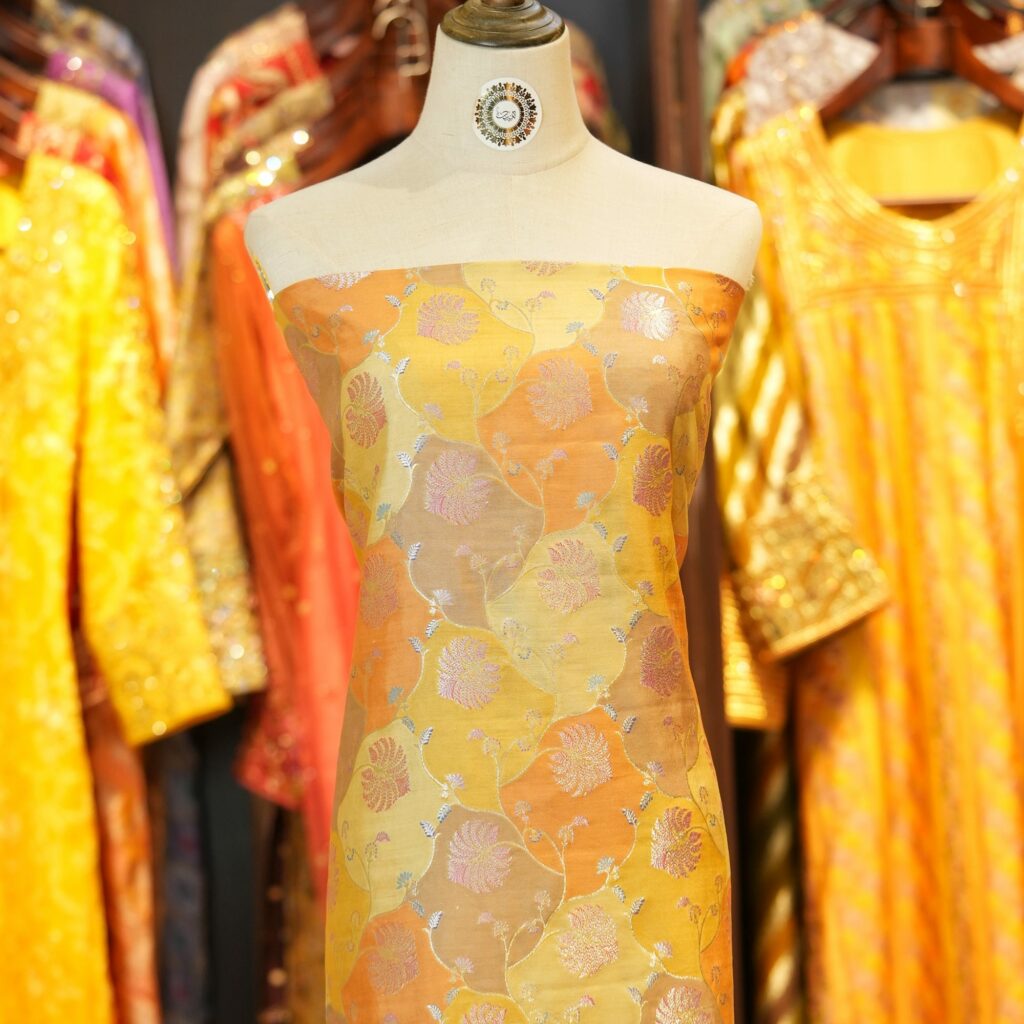 Amber orange and yellow Rangkaat silk fabric with silver and pink zari floral weave