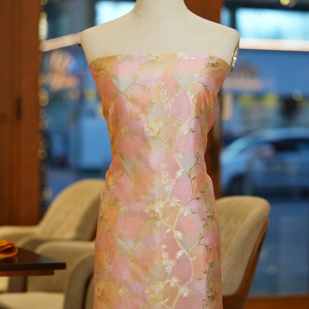 Blush peach Rangkaat silk fabric with multicolored floral zari weaving and soft pastel highlights