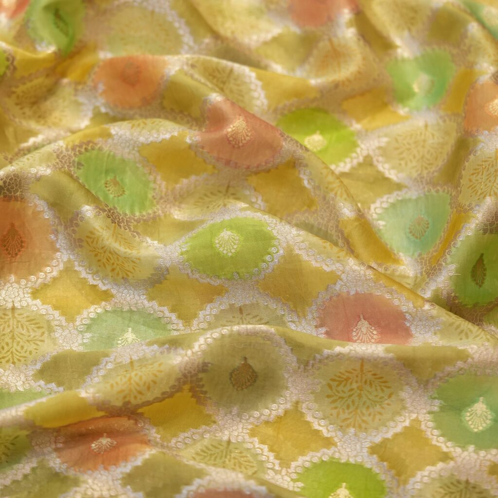 Pure organza silk fabric with multicolor circular motifs and golden zari weaving on a pastel base