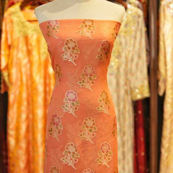 Peach coral khaddi chiffon fabric with hand-brushed dye and floral boota motifs with zari accents