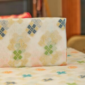 Sheer chiffon fabric with multicolored ikkat-style cotton floral motifs and shimmering golden zari weave on an off-white base.