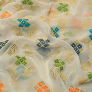 Sheer chiffon fabric with multicolored ikkat-style cotton floral motifs and shimmering golden zari weave on an off-white base.