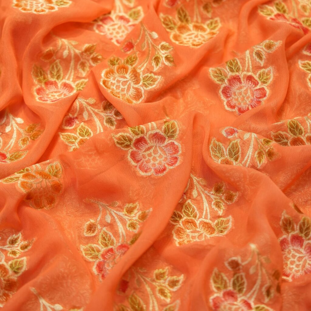 Peach coral khaddi chiffon fabric with hand-brushed dye and floral boota motifs with zari accents