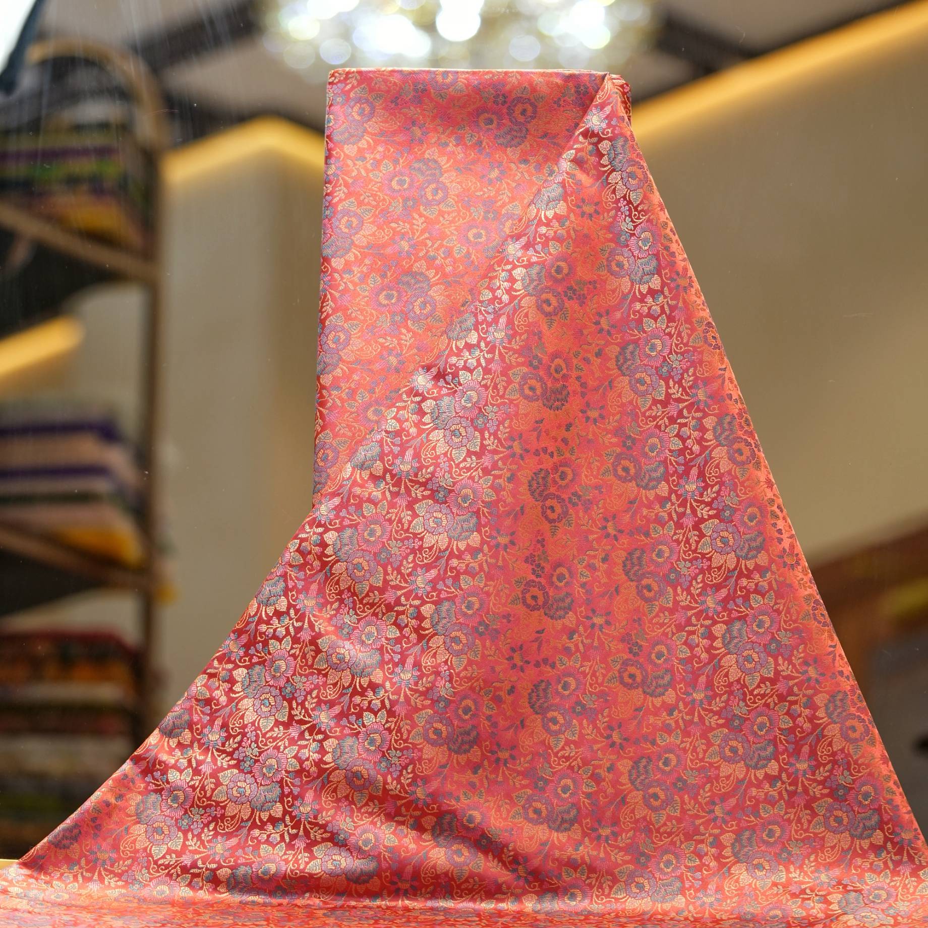 Tanchoi resham silk fabric with intricate floral weaving in crimson, lavender, and gold