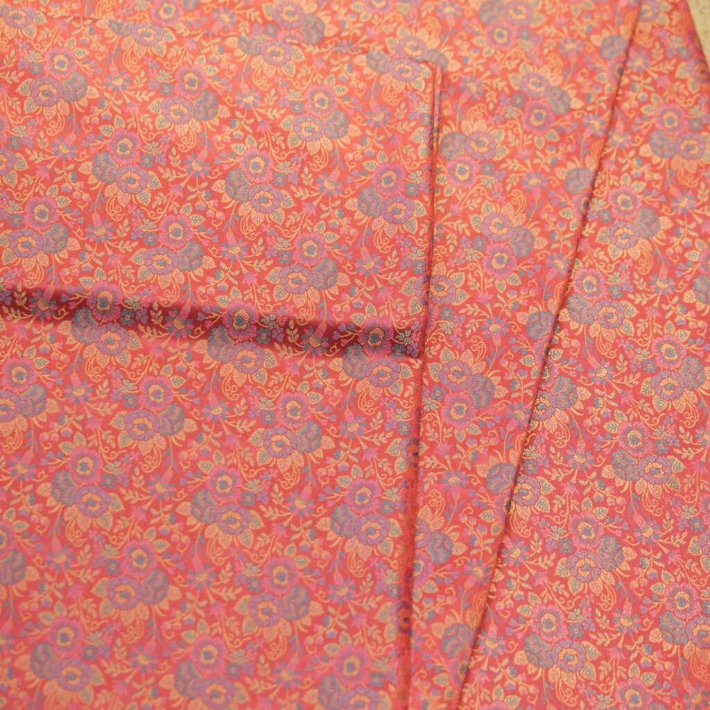 Tanchoi resham silk fabric with intricate floral weaving in crimson, lavender, and gold