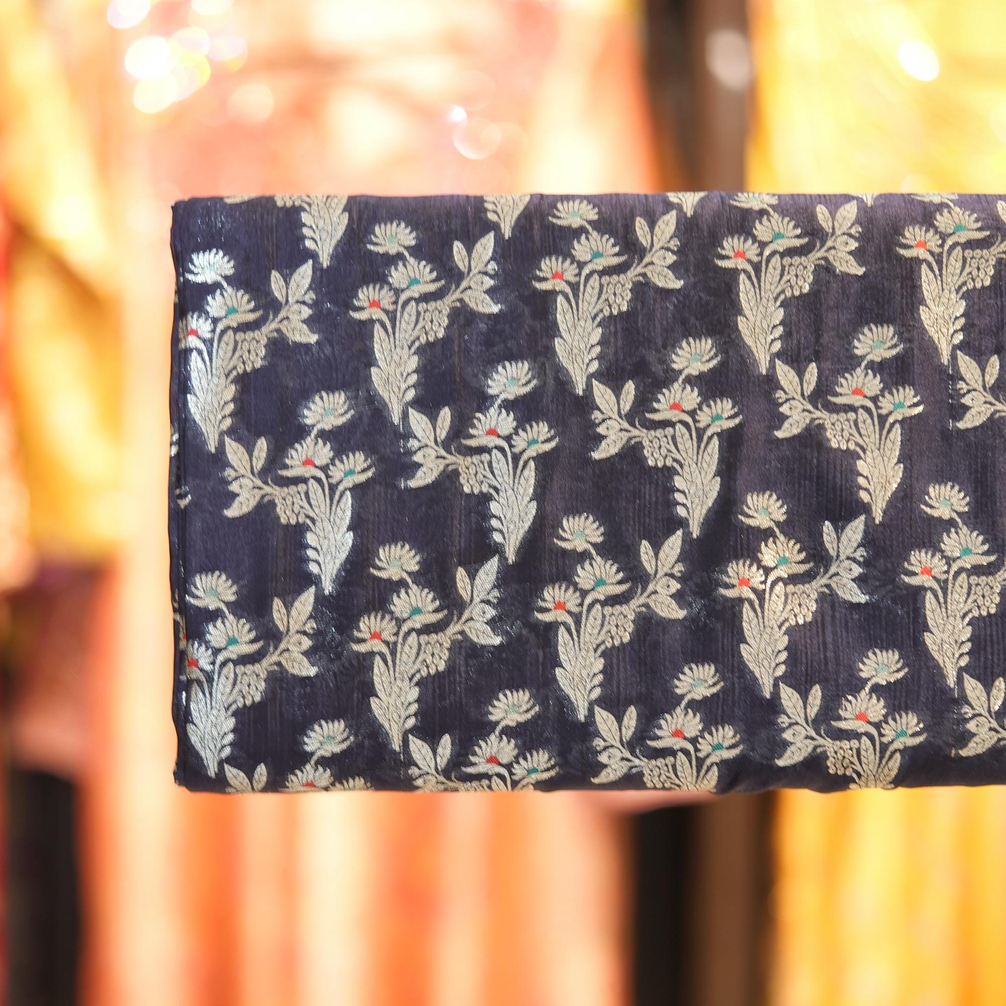 A refined navy blue dupion silk adorned with silver zari florals and subtle pops of meena work — perfect for contemporary thobes, statement pieces, or couture accents.