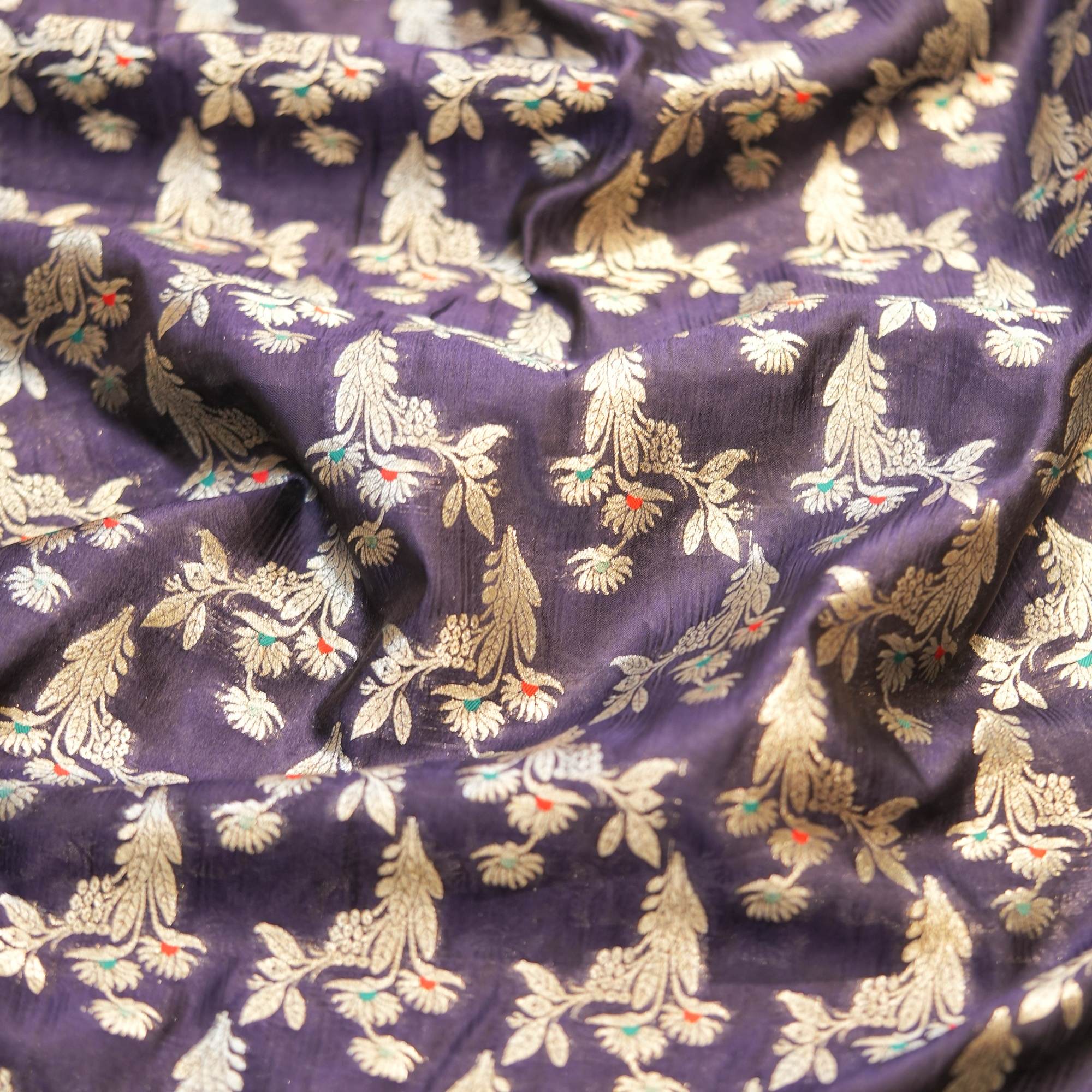 A refined navy blue dupion silk adorned with silver zari florals and subtle pops of meena work — perfect for contemporary thobes, statement pieces, or couture accents.