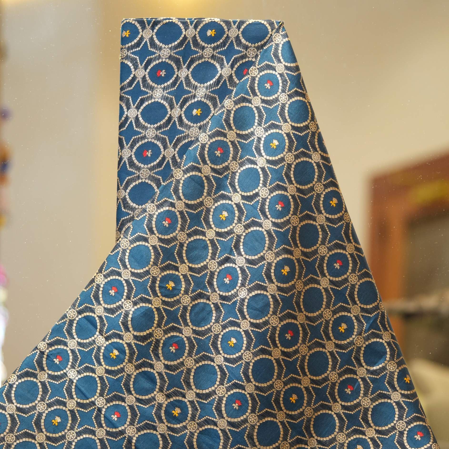 Teal dupion silk fabric woven with silver-gold Zari lattice circles and tiny red & yellow Meenakari accents – Zahiri collection