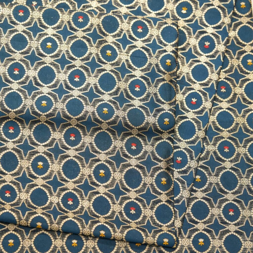 Teal dupion silk fabric woven with silver-gold Zari lattice circles and tiny red & yellow Meenakari accents – Zahiri collection