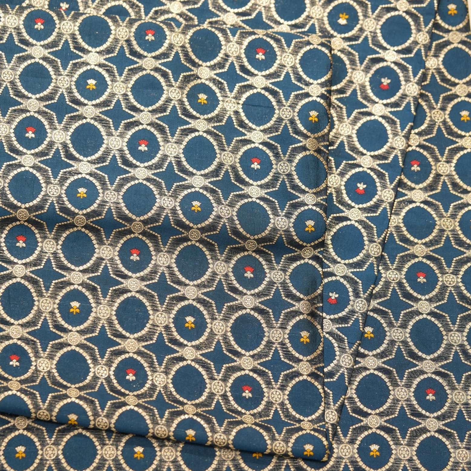 Teal dupion silk fabric woven with silver-gold Zari lattice circles and tiny red & yellow Meenakari accents – Zahiri collection