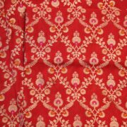 Red dupion silk fabric with intricate zari vines and colorful meenakari floral motifs