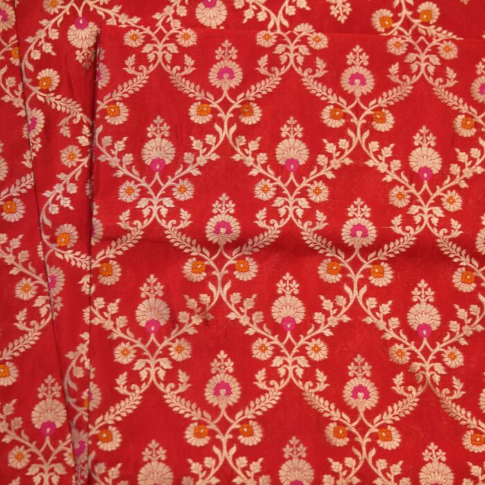 Red dupion silk fabric with intricate zari vines and colorful meenakari floral motifs