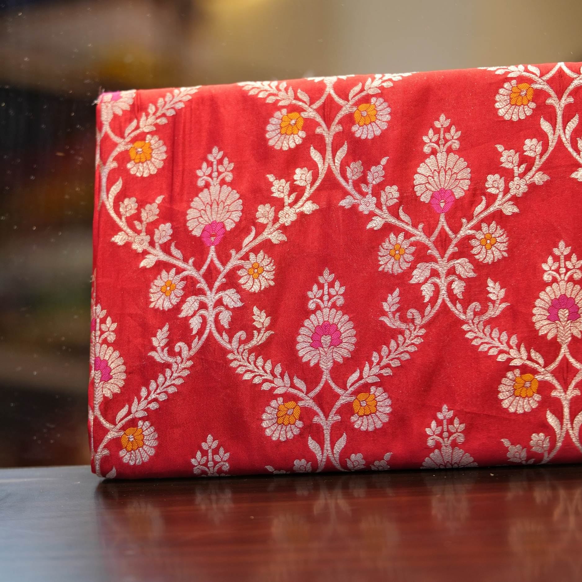 Red dupion silk fabric with intricate zari vines and colorful meenakari floral motifs
