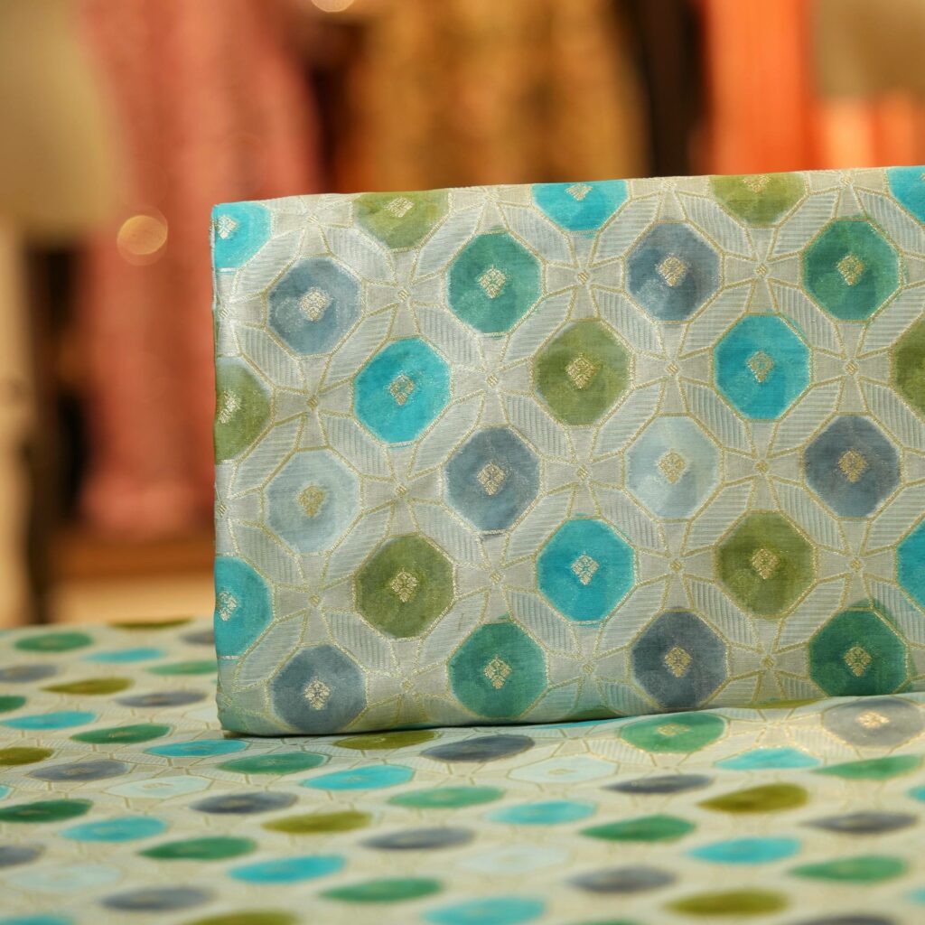 Katan silk fabric with golden Zari weave and green-teal Rangkaat dye in octagonal motifs