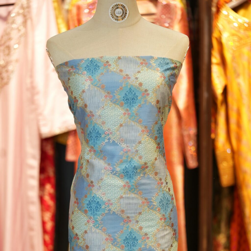 Elegant blue cotton jacquard fabric with Zari geometric weave and printed floral accents – Firdaws-e-Zar